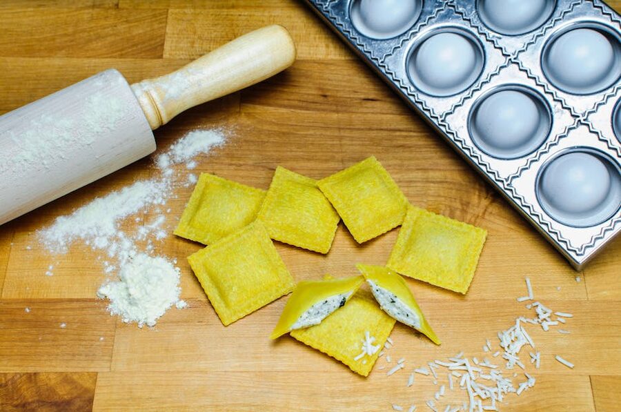 Homemade ravioli with rolling pin on wooden board