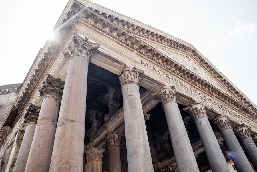 Looking up at the Pantheon facade showing the Latin inscription and Corinthian columns