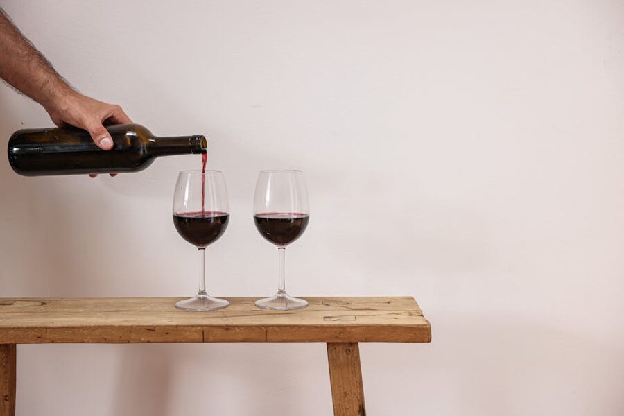 Pouring red wine into glasses on a rustic wooden table