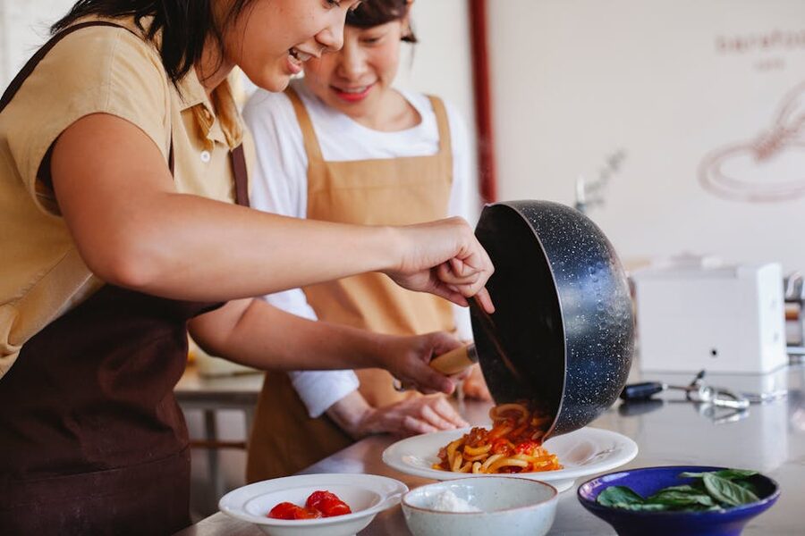 Two women preparing pasta in an Italian cooking class