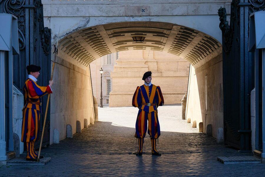 Swiss Guards in traditional uniforms standing at a Vatican City entrance