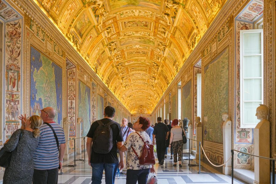 Visitors walking through a golden corridor in the Vatican Museums