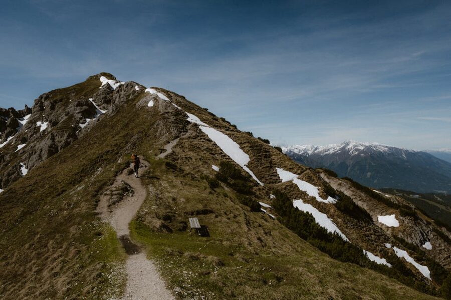 Solo hiker walking a snowy alpine ridge trail