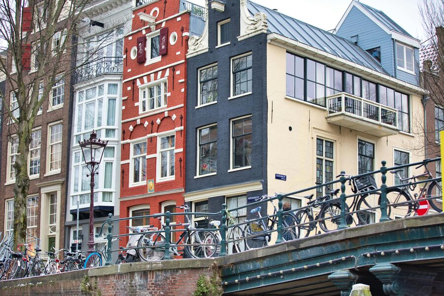 Amsterdam bicycles on a bridge with canal houses behind