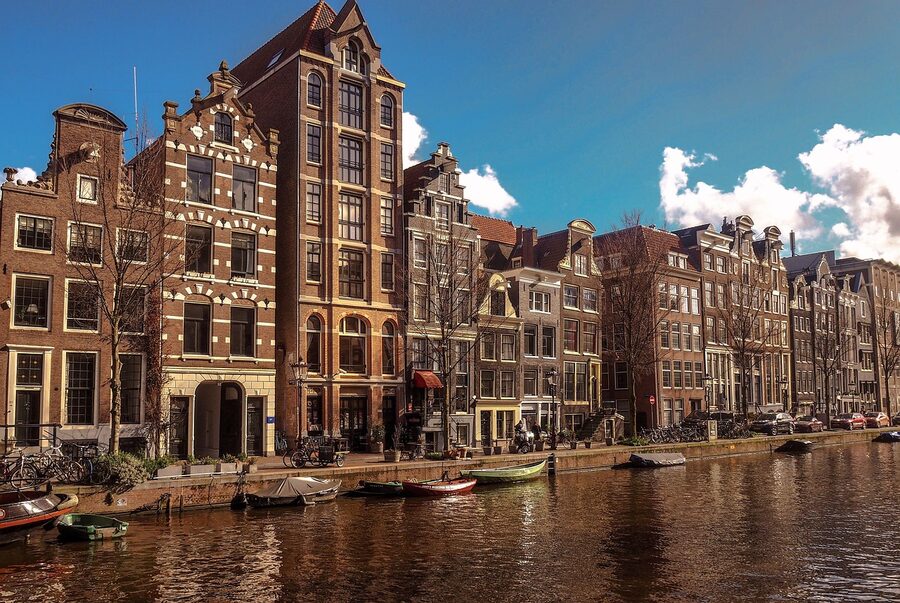 Amsterdam canal lined with traditional Dutch houses and a row of moored boats