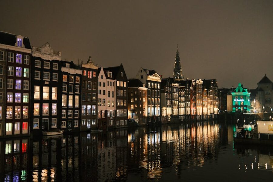 Amsterdam canal houses lit at night with reflections on still canal water
