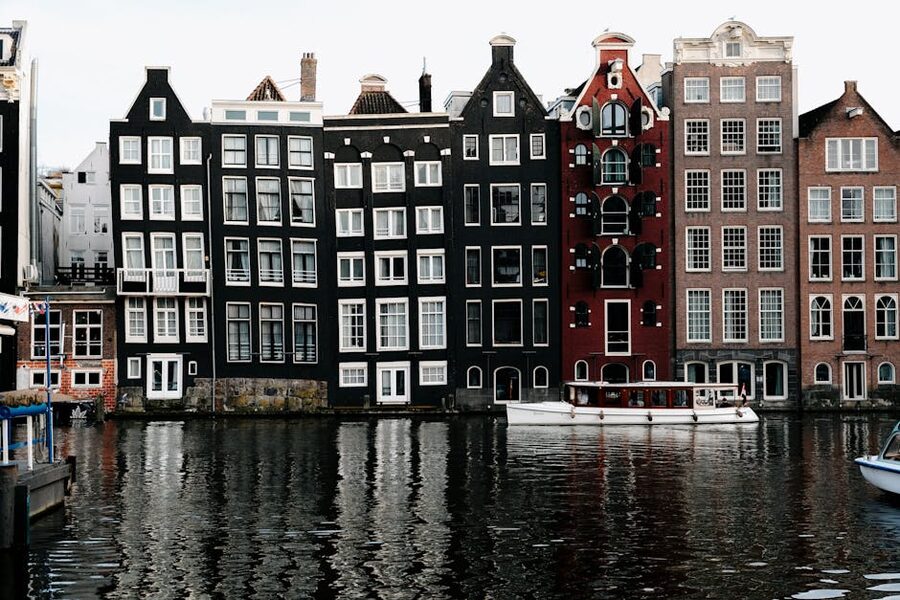 Amsterdam canal houses reflected in still canal water during midday