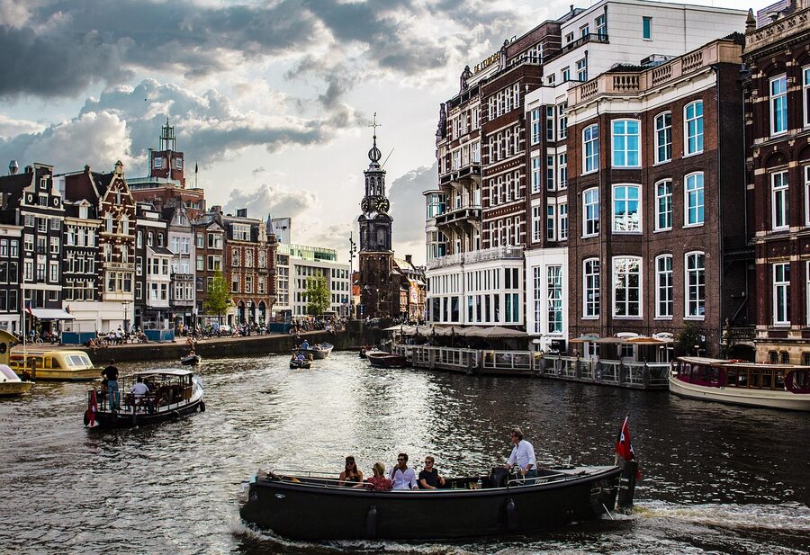 Tourists boarding a canal tour boat on a sunny Amsterdam afternoon