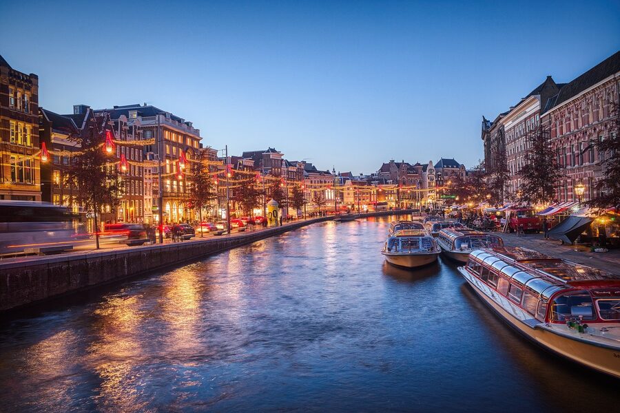 Amsterdam canal at evening illuminated with bridge lights and building reflections in the water