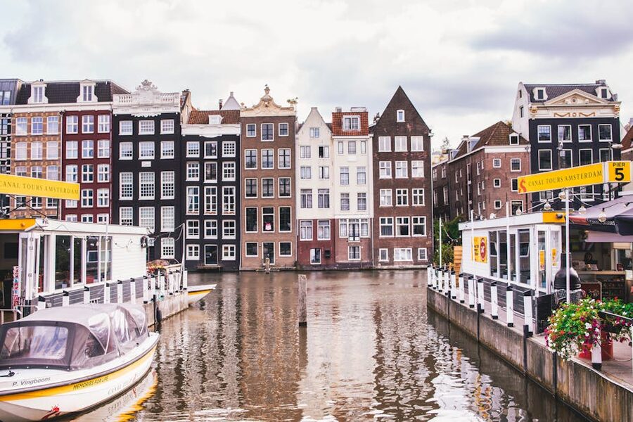 Row of historic Amsterdam canal houses with stepped gables along a tree-lined canal