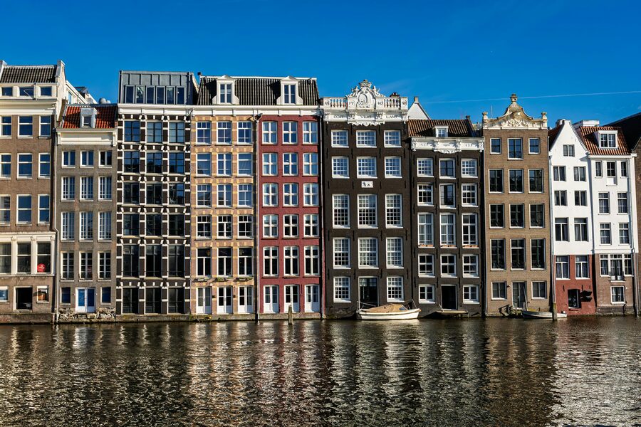 Row of traditional Amsterdam canal houses reflecting in water
