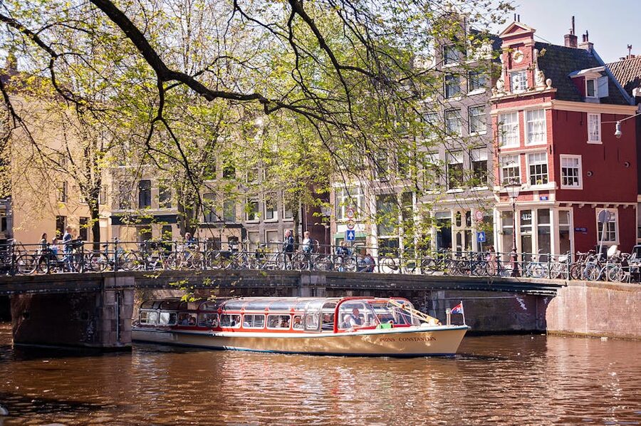 Amsterdam canal tour boat passing under a classic bridge