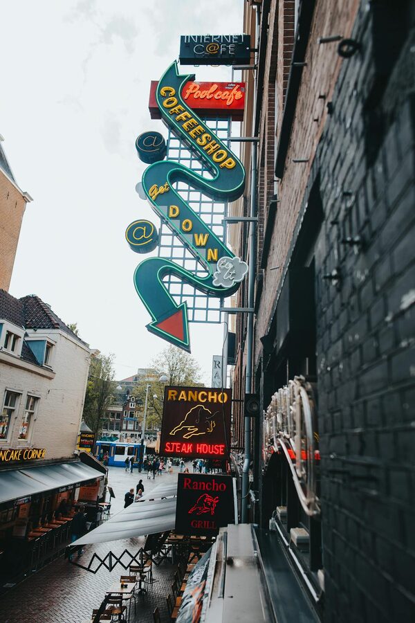 Amsterdam street with colorful neon signs of a coffee shop