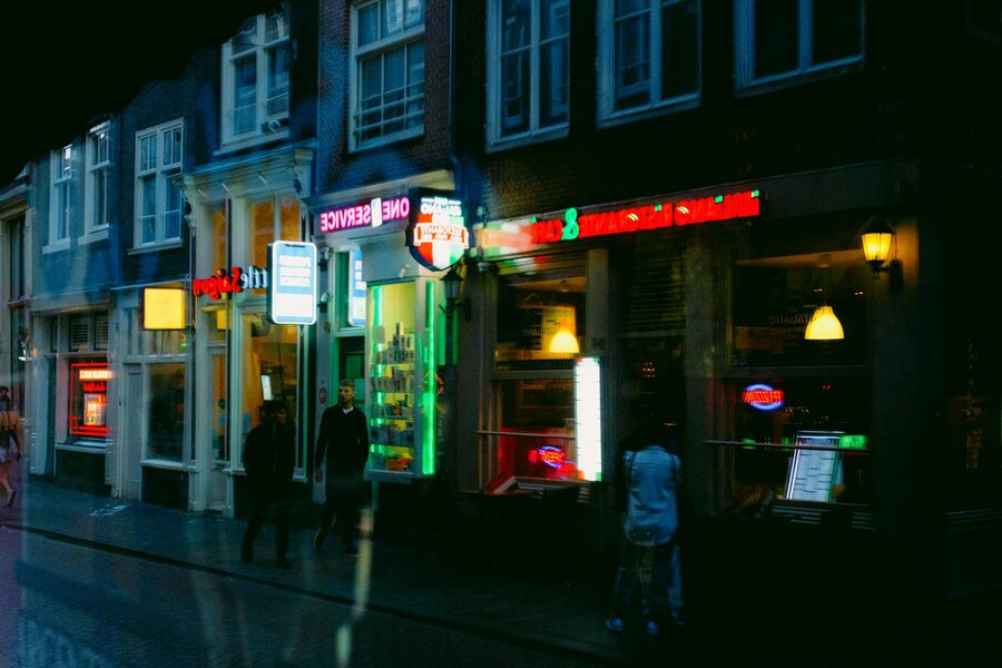 Amsterdam neon-lit storefronts and pedestrians at night