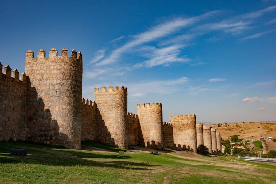 Stone walls of Avila under bright sunshine showing tower and crenellations
