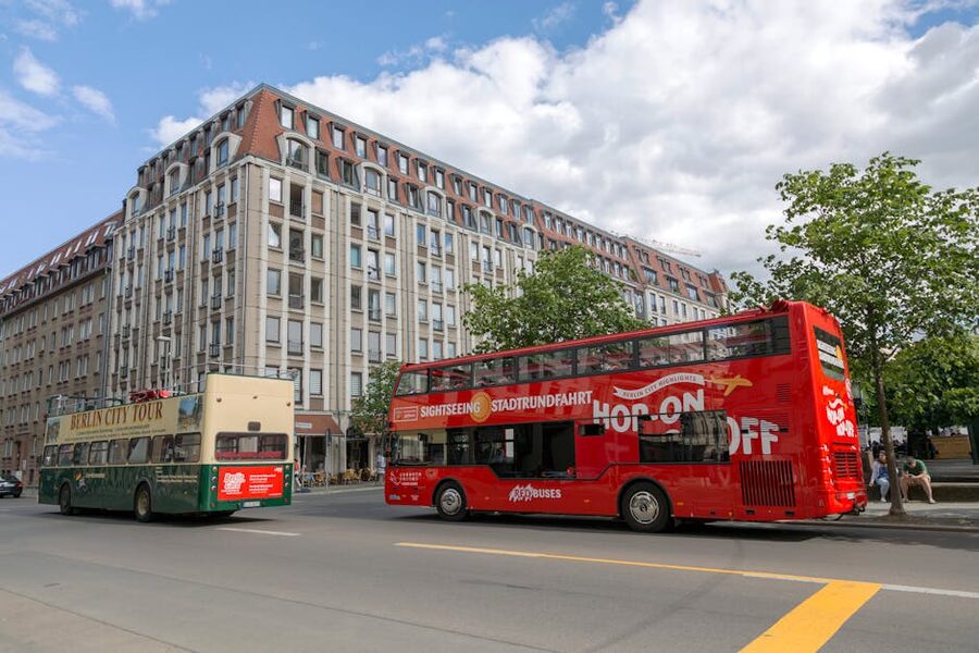 Berlin sightseeing buses parked near a historic building on a sunny day