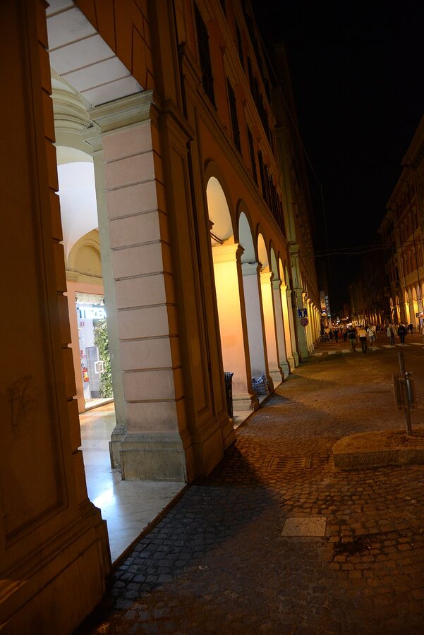 Bologna porticoes lit at night with warm yellow light