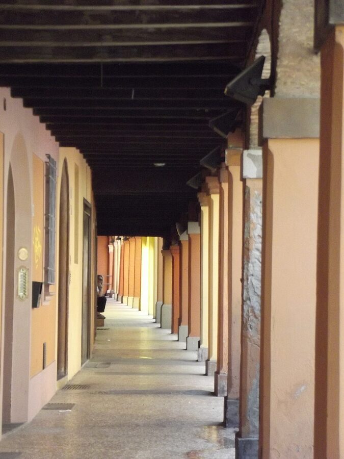 Long perspective shot of the porticoes of Bologna receding into the distance