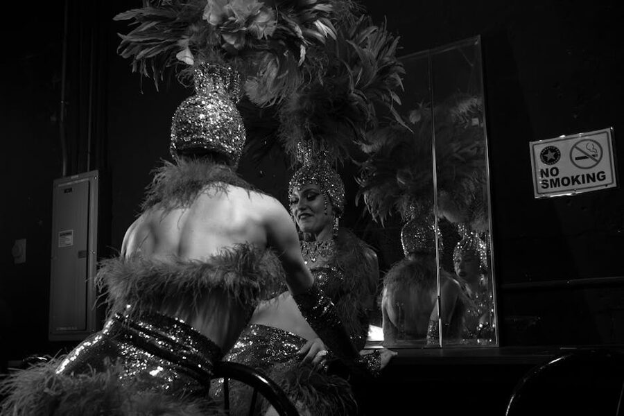 A cabaret dancer in feathered headdress and sequined costume backstage