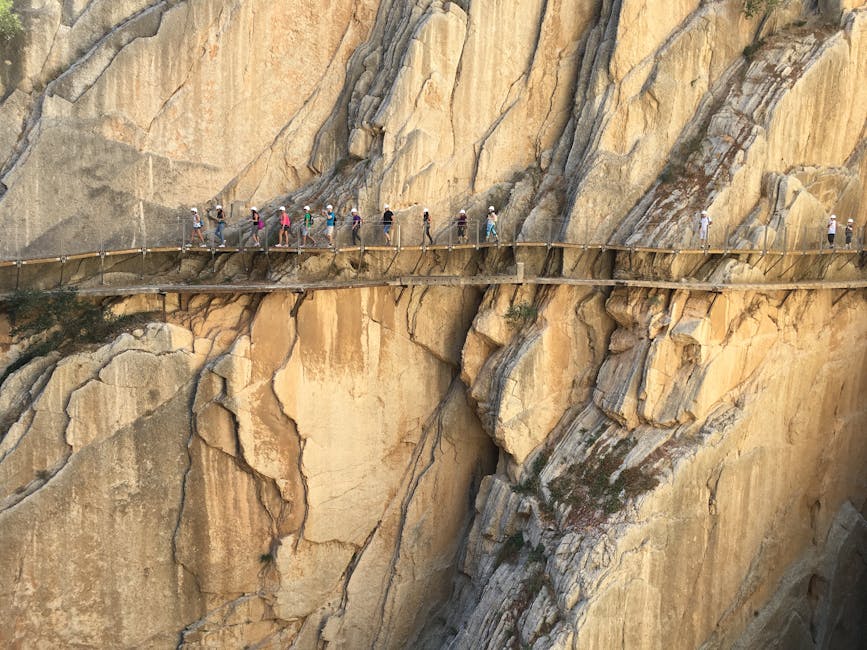 Hikers crossing a suspended bridge of Caminito del Rey on the cliff edge