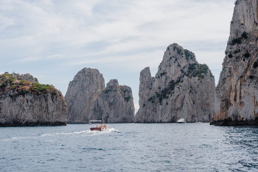 Capri limestone cliffs with boats in azure water