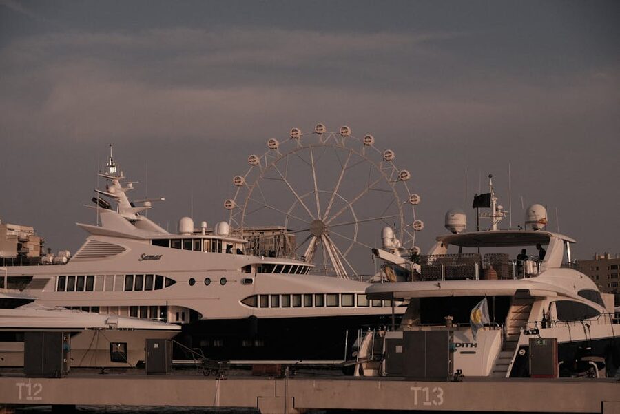 Luxury yachts in Barcelona harbour with ferris wheel at sunset