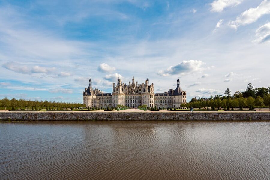 Chambord castle reflected in water under a blue sky