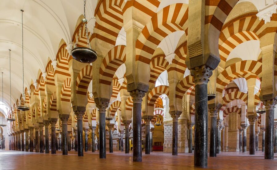 A long colonnade of red and white horseshoe arches inside the Mezquita