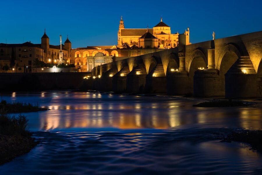 The Roman Bridge of Cordoba with the illuminated Mezquita behind at night