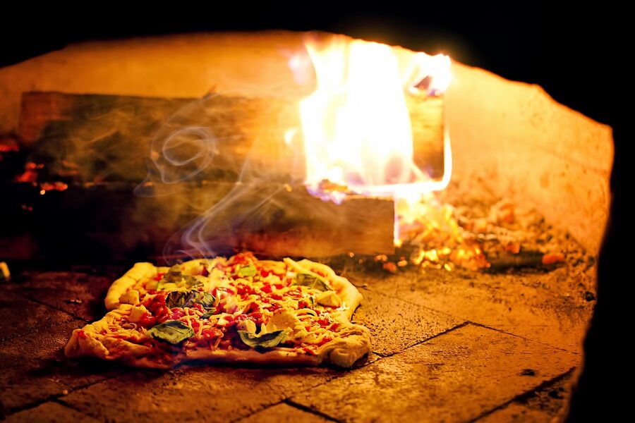 Pizza coming out of a wood-fired oven at a Naples pizzeria