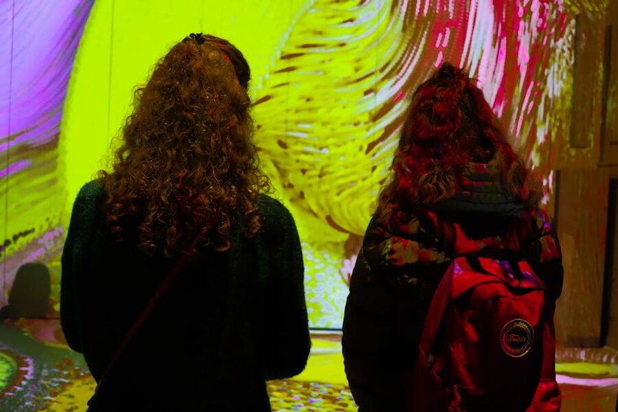 Pair of visitors watching colourful projections in art gallery setting
