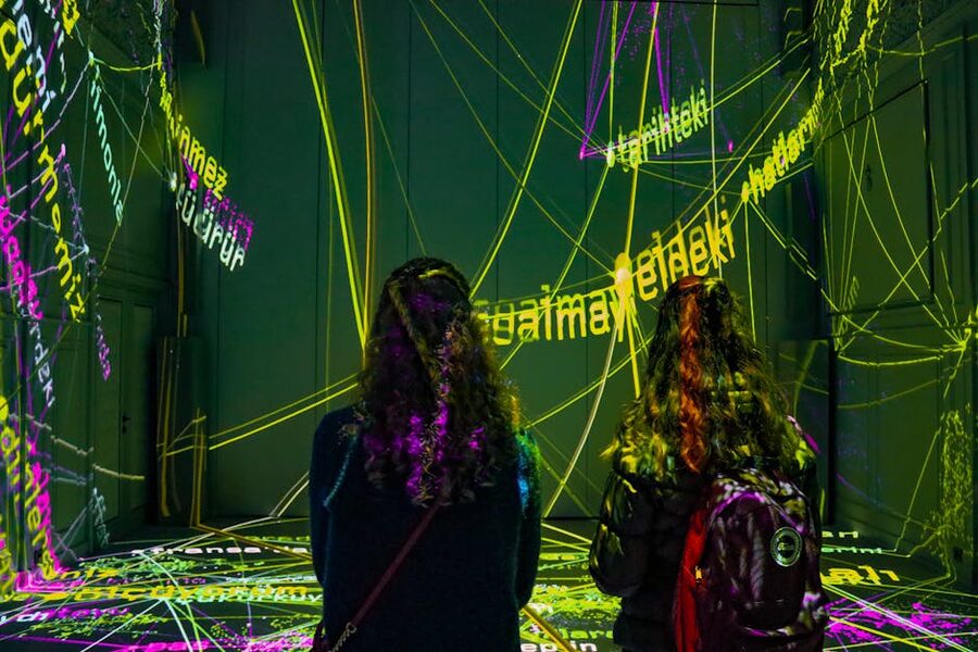 Visitors inside a dark projection room with text-based digital art