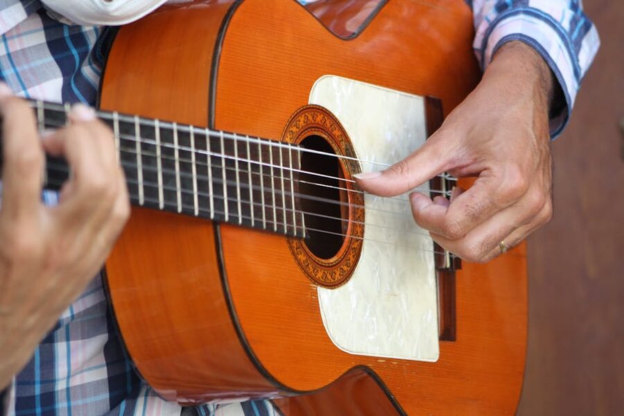 Flamenco guitarist hands strumming a wooden guitar