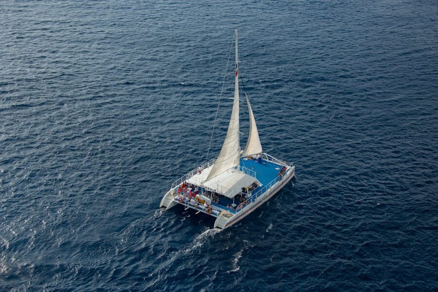 Catamaran with passengers under sail on a clear blue sea
