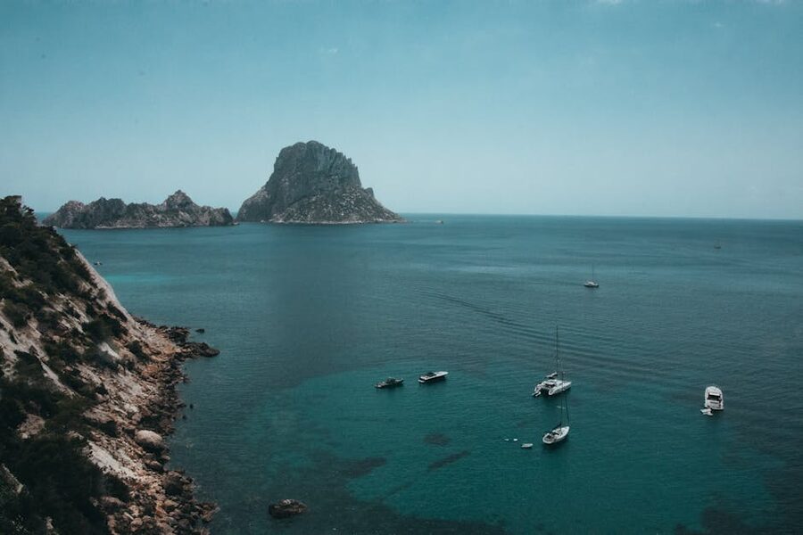 Boats anchored near the rocky coast of Es Vedra island Ibiza