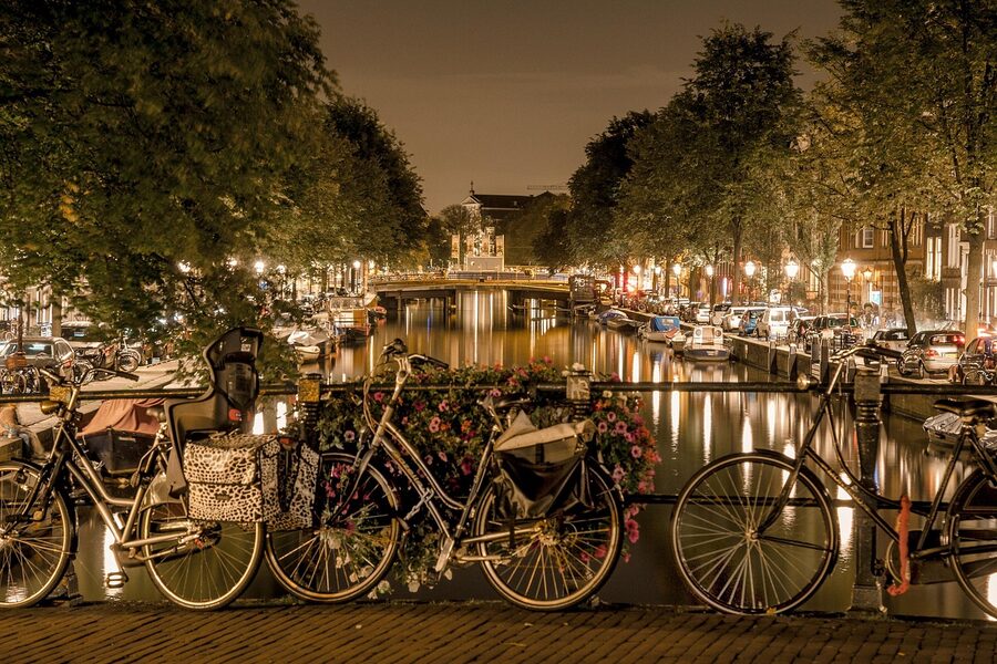 Amsterdam bicycles lined up near canal at night