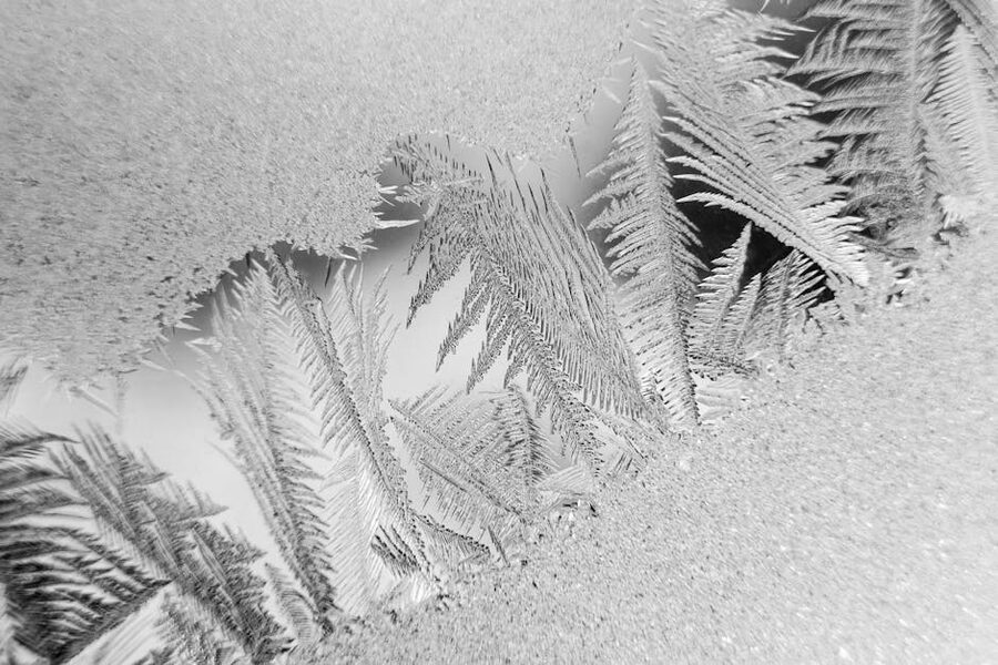 Frost patterns forming on a cold window pane