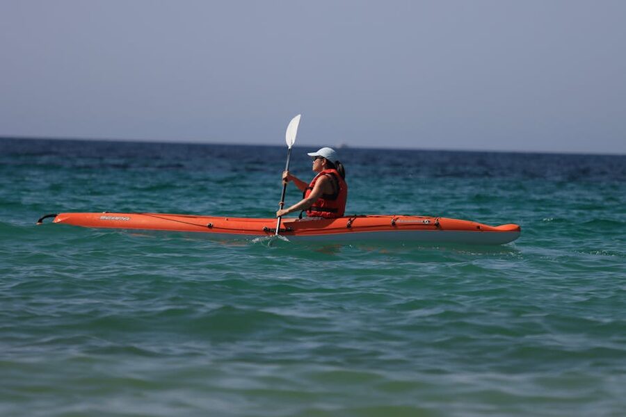 Woman paddling an orange kayak on the open ocean