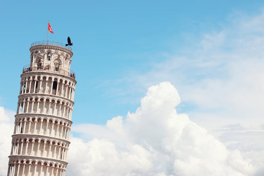 The Leaning Tower of Pisa under a clear sky with white clouds