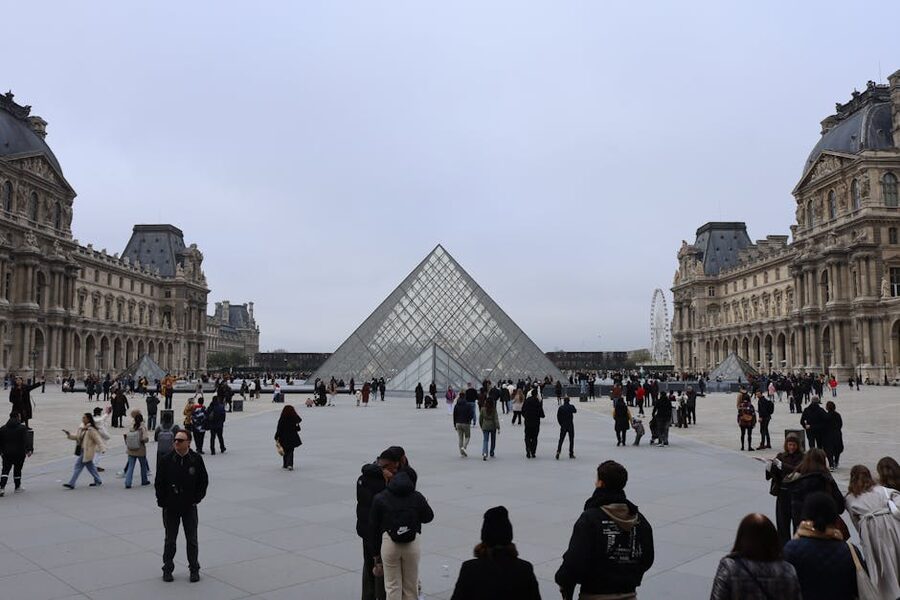Louvre courtyard with visitors and the glass pyramid in Paris