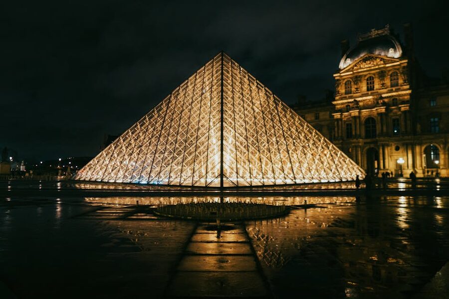 Louvre Pyramid illuminated at night with the palace facade