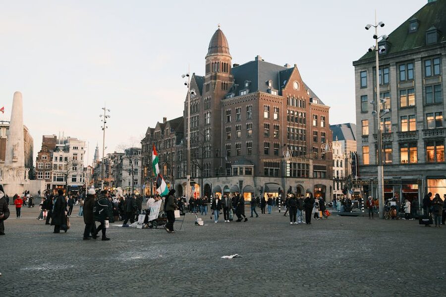 Dam Square Amsterdam at dusk with crowd around National Monument