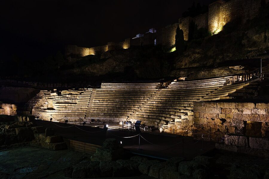 Malaga Roman theatre lit at night with the Alcazaba illuminated above