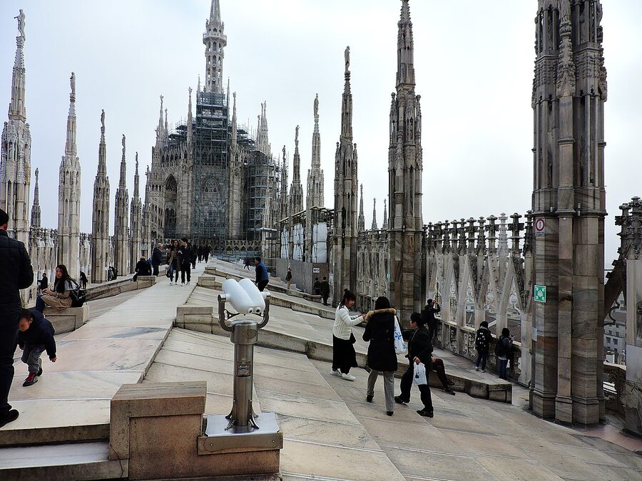 Visitors walking on the terraces of Milan Duomo between flying buttresses