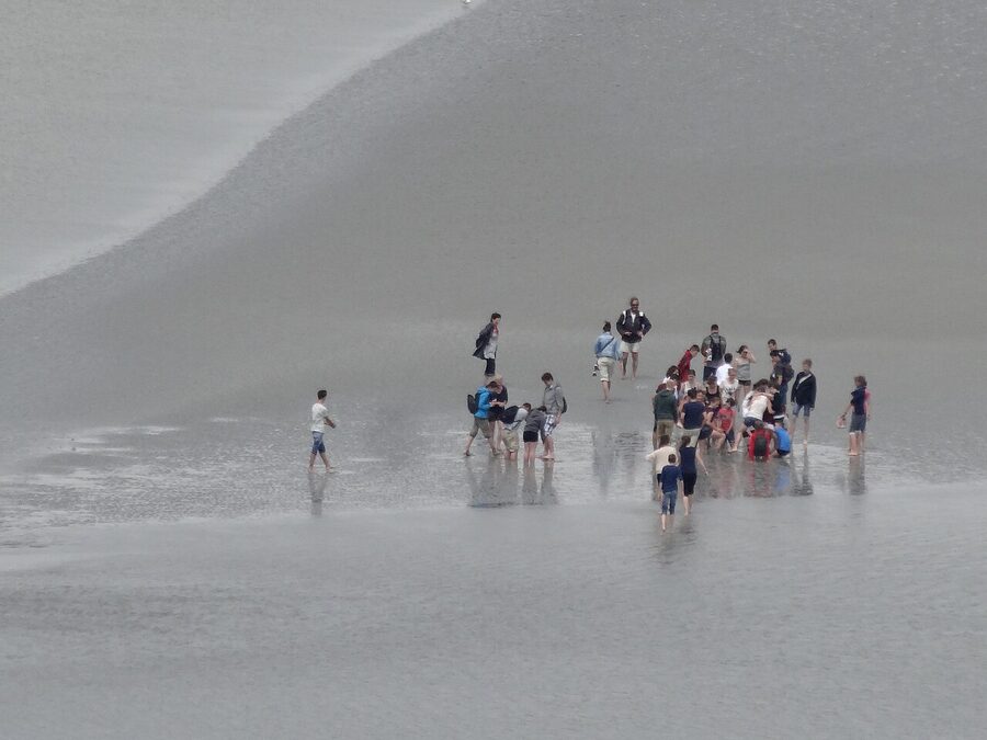 Walkers on the mud at low tide in Mont-Saint-Michel bay