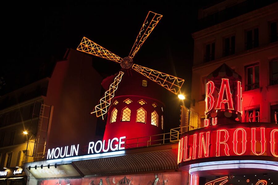The illuminated red windmill at the Moulin Rouge in Paris at night