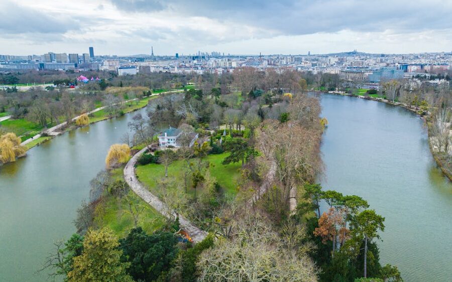 Aerial view of a Parisian park with river trees and city skyline