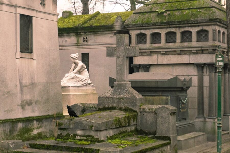 Atmospheric cemetery scene with statues and crow at Pere Lachaise Paris