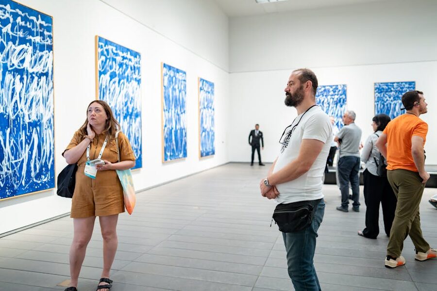 Visitors viewing blue abstract paintings in a contemporary art gallery