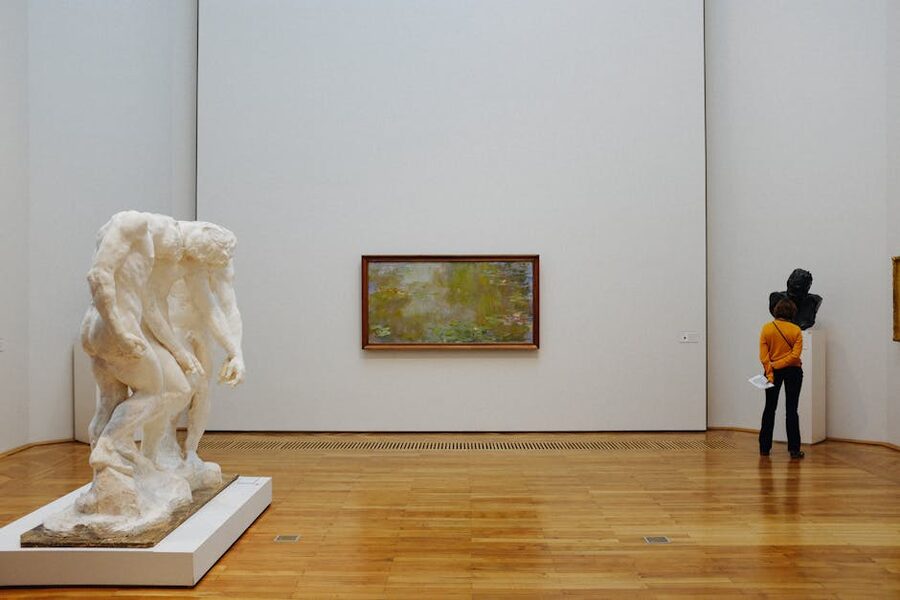 Visitor in modern art gallery with sculpture and paintings